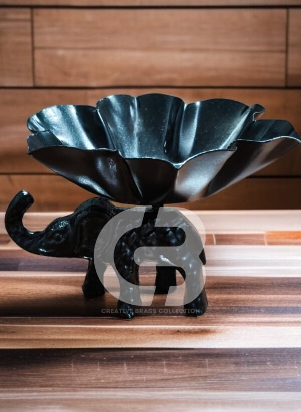 A high-resolution product shot of a handcrafted elephant bowl with colorful enamel details, used as a dry fruit dish. The elephant's trunk is raised in a symbol of good luck. Product code CB-ETLH01.