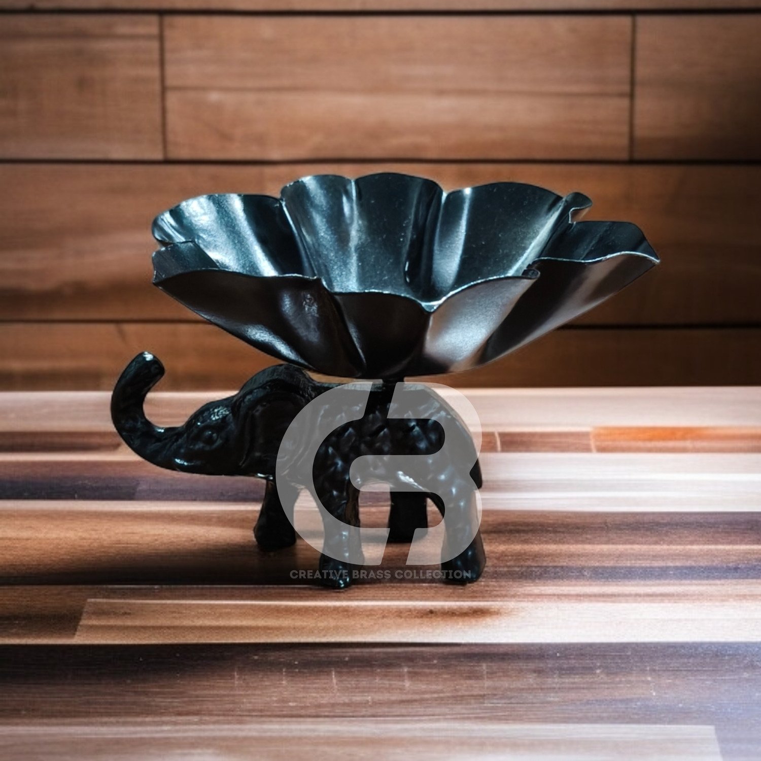 A high-resolution product shot of a handcrafted elephant bowl with colorful enamel details, used as a dry fruit dish. The elephant's trunk is raised in a symbol of good luck. Product code CB-ETLH01.